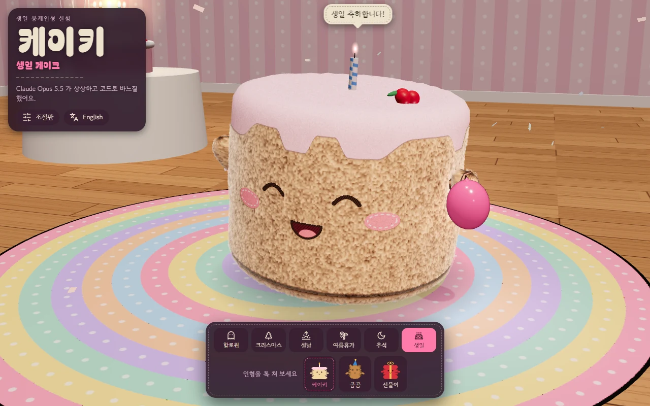 컴퓨터 화면 크기의 실제 화면이다. 분홍 줄무늬 벽지와 나무 바닥의 생일 파티 방에서, 분홍 크림이 흘러내린 케이크 모양 봉제인형이 눈을 감고 입을 벌려 웃고 있다. 꼭대기에 파란 줄무늬 초 하나와 체리가 꽂혀 있고, 오른쪽 끈 끝에 분홍 풍선이 떠 있다. 머리 위 말풍선에 '생일 축하합니다!' 라고 적혀 있다. 바닥에는 파스텔 무지개 둥근 깔개가 있다. 왼쪽 위에 '케이키 · 생일 케이크' 머리말과 '조절판' · 'English' 단추가 있고, 아래 가운데 도크에 이벤트 여섯과 '인형을 톡 쳐 보세요' 안내, 인형 셋을 고르는 칸이 있다.